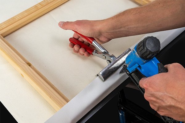 Craftsman hand-stretching the canvas with clean, gallery-wrapped corners
